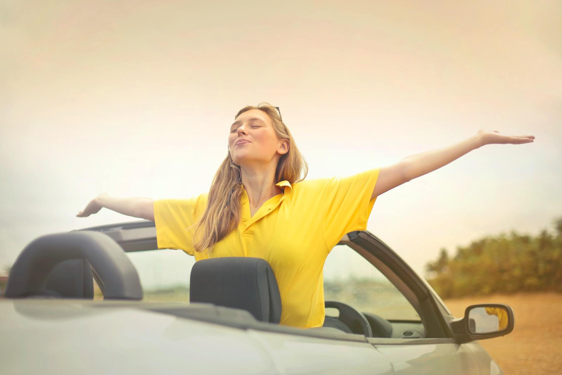 femme blonde heureuse bras ouvert dans une voiture décapotable