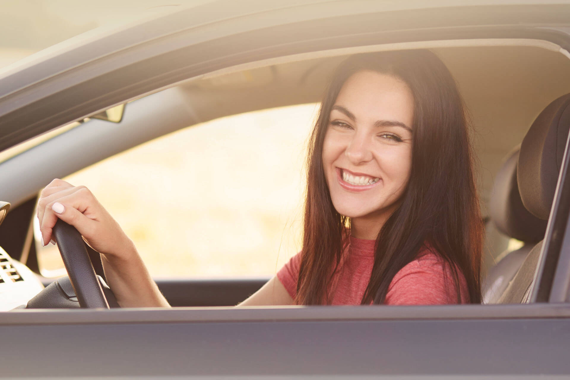 femme brune souriante au volant de sa voiture