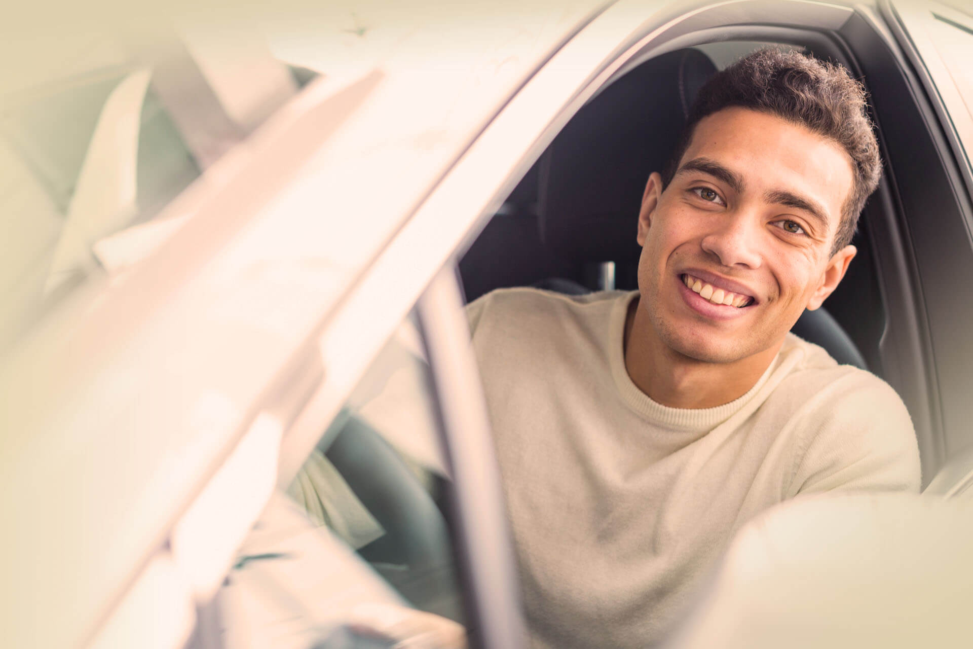 jeune homme souriant au volant de sa voiture