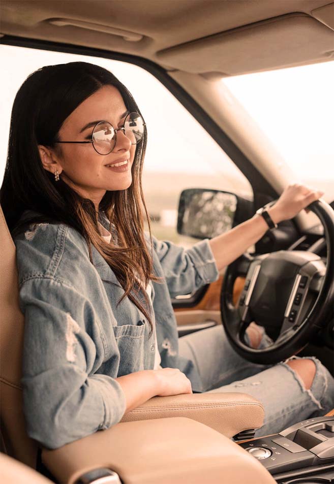 femme brune souriante au volant de sa voiture