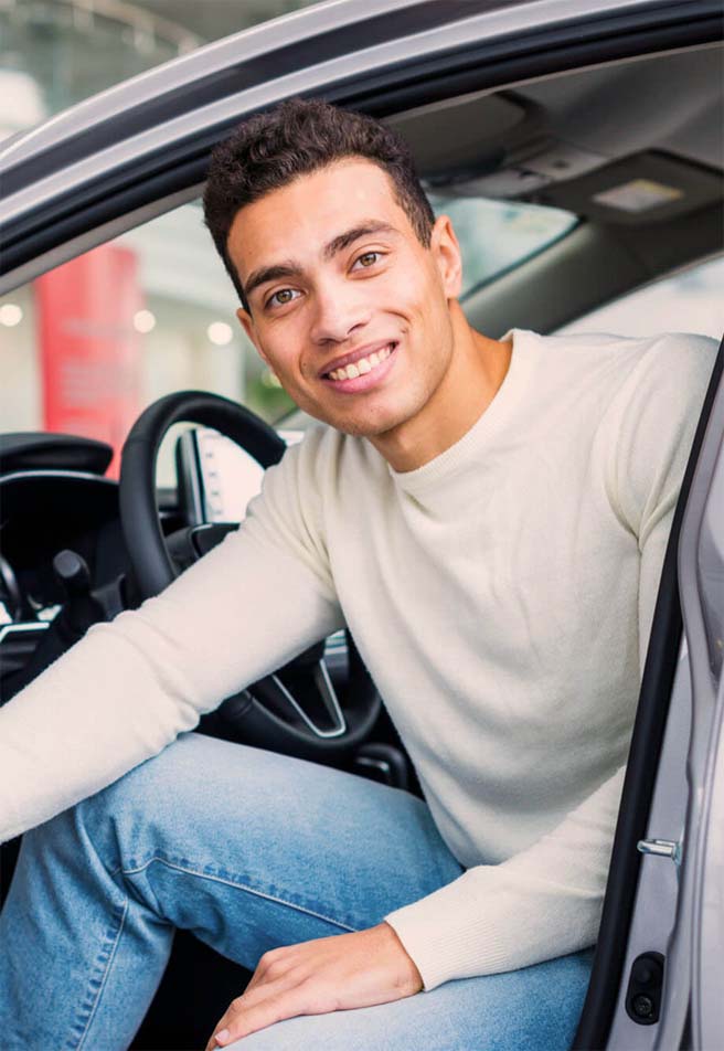 jeune homme souriant au volant de sa voiture