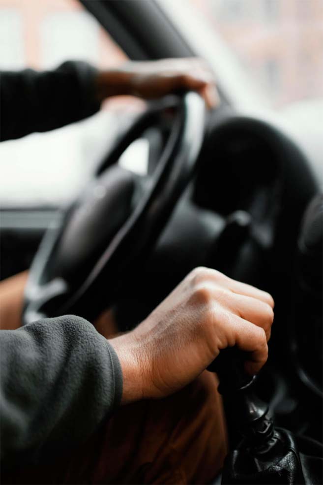 intérieur de voiture dont une personne au volant tenant avec sa main droite le levier de vitesse